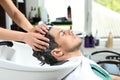 Stylist washing client`s hair at sink in salon Royalty Free Stock Photo