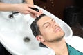 Stylist washing client`s hair at sink in salon Royalty Free Stock Photo