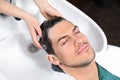 Stylist washing client`s hair at sink