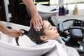 Stylist washing client`s hair at sink