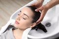 Stylist washing client`s hair at sink