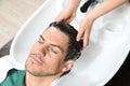 Stylist washing client`s hair at sink