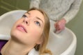 Stylist washing and combing woman hair in hairsalon pool