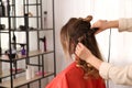 Stylist working with client in salon, making hairstyle