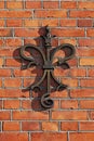 A stylistic French lily in metal mounted on a brick facade