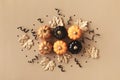 Stylized autumn background with golden leaves and pumpkins decorated with black ribbons and confetti. Top view, flat lay