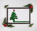 Stylized Christmas tree made from green ribbon with red shiny star and Christmas balls in photo frame on white Royalty Free Stock Photo