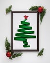 Stylized Christmas tree made from green ribbon with red shiny star and Christmas balls in photo frame on white Royalty Free Stock Photo