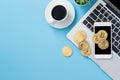 Stylized clean blue office working desk with bitcoin, smartphone, laptop and coffee cup, workspace design, mock up, top view, flat Royalty Free Stock Photo