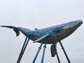 Stylized decorated figure of a blue whale on stands against a light sky