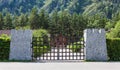 Stylized entrance to the recreation center through the castle gate with stone columns and iron bars with green trees and a wooden Royalty Free Stock Photo