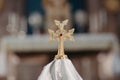 Stylized golden cross placed on a white tablecloth.