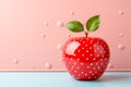 Stylized red apple with white polka dots, complete with green leaves against pink background