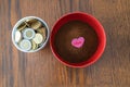 Styrofoam cup full of coins with red bowl of instant coffee