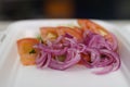 Styrofoam lunch box with fresh vegetables and red onions