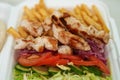 Styrofoam lunch box with Greek kalamaki dish. Traditional souvlaki meat and fries served for take away in a fast food restaurant
