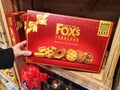 Subang Jaya,Malaysia-12 March 2022 : Hand pick up a FOX FABULOUS Biscuit Selection box for sell on the supermarket shelf.
