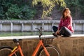 Subject ecological bicycle transport. A young caucasian woman in jeans and a shirt student sits resting in a park near the lake Royalty Free Stock Photo