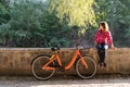 Subject ecological bicycle transport. A young caucasian woman in jeans and a shirt student sits resting in a park near the lake Royalty Free Stock Photo