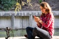 Subject ecological bicycle transport. Young Caucasian woman in shirt student sits resting in a park near the lake for rent orange Royalty Free Stock Photo