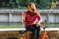 Subject ecological bicycle transport. Young Caucasian woman in shirt student sits resting in a park near the lake for rent orange Royalty Free Stock Photo