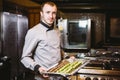 Subject profession and cooking pastry. Young caucasian male pastry chef posing looking at camera in uniform in the kitchen holding