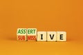 Submissive or assertive symbol. Concept words Submissive and assertive on wooden cubes. Beautiful orange background. Business,