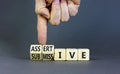 Submissive or assertive symbol. Concept words Submissive and assertive on wooden cubes. Businessman hand. Beautiful grey