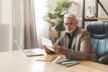 Subpoena. A frustrated mature man sits at a desk in the office and holds a tax letter in his hands. Financial problems and debt