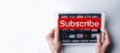 Subscribe banner. Online video subscription red button. Internet service on laptop digital tablet blured technology