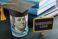 Subsidized loan sign and student graduation cap. Royalty Free Stock Photo