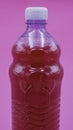 Red detergent or disinfectant inside a transparent plastic bottle on a lilac background