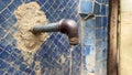 Subsurface water coming out of a metal pipe with blue mosaic in the background