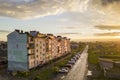 Suburb landscape, apartment building. Parked cars along bad road on spring day on blue sky copy space background Royalty Free Stock Photo