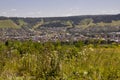 Suburb and villages. Big mountains and dark green forests far away. Trees and their shadows on the grass. Summer day with bright b Royalty Free Stock Photo