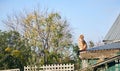 Ginger red tabby cat sitting on a tin roof in a suburban setting against a blue sky. Royalty Free Stock Photo