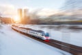 Suburban electric passenger train rushes through the snow-covered landscape of the city, motion blur effect Royalty Free Stock Photo