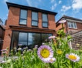 New build red brick extension and three tall windows. Rock garden with Mexican daisies, Erigeron Karvinskianus in the foreground.