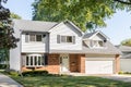 A suburban home with brick and grey vinyl siding.