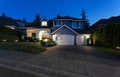 Suburban home exterior on a summer late evening with lights on yard and house