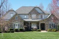 Suburban house with stone exterior and green lawn in an affluent neighborhood