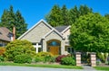 Suburban residential house in green trees and bushes on blue sky background.