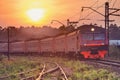 Suburbian train approaches to the station at sunset