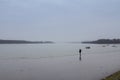 Picture of a man having a walk alone near the Danube river while most of the landscape is fading due to a heavy smog and rain