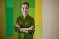 Portrait of a young beautiful female office worker keeping arms crossed, looking at camera and smiling while standing in Royalty Free Stock Photo