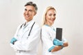 Succesful medical team. Two cheerful doctors, man and woman in medical uniform keeping arms crossed, looking at camera Royalty Free Stock Photo