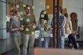 Succesful team. Group of happy business people, coworkers looking at sticky notes on a glass board, discussing new