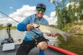 Success fishing. Fisherman with asp aspius fish on boat at wild river Royalty Free Stock Photo