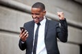 Success is on the horizon. a young businessman cheering while using a phone in the city.