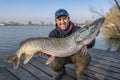 Success pike fishing. Happy fisherman with big fish trophy in hands Royalty Free Stock Photo